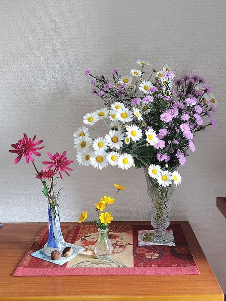 3つの花瓶に入れた切り花が玄関に飾られている様子。